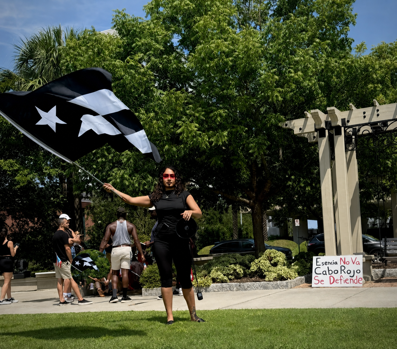 Participant holding a black Puerto Rican flag near the rally sign.