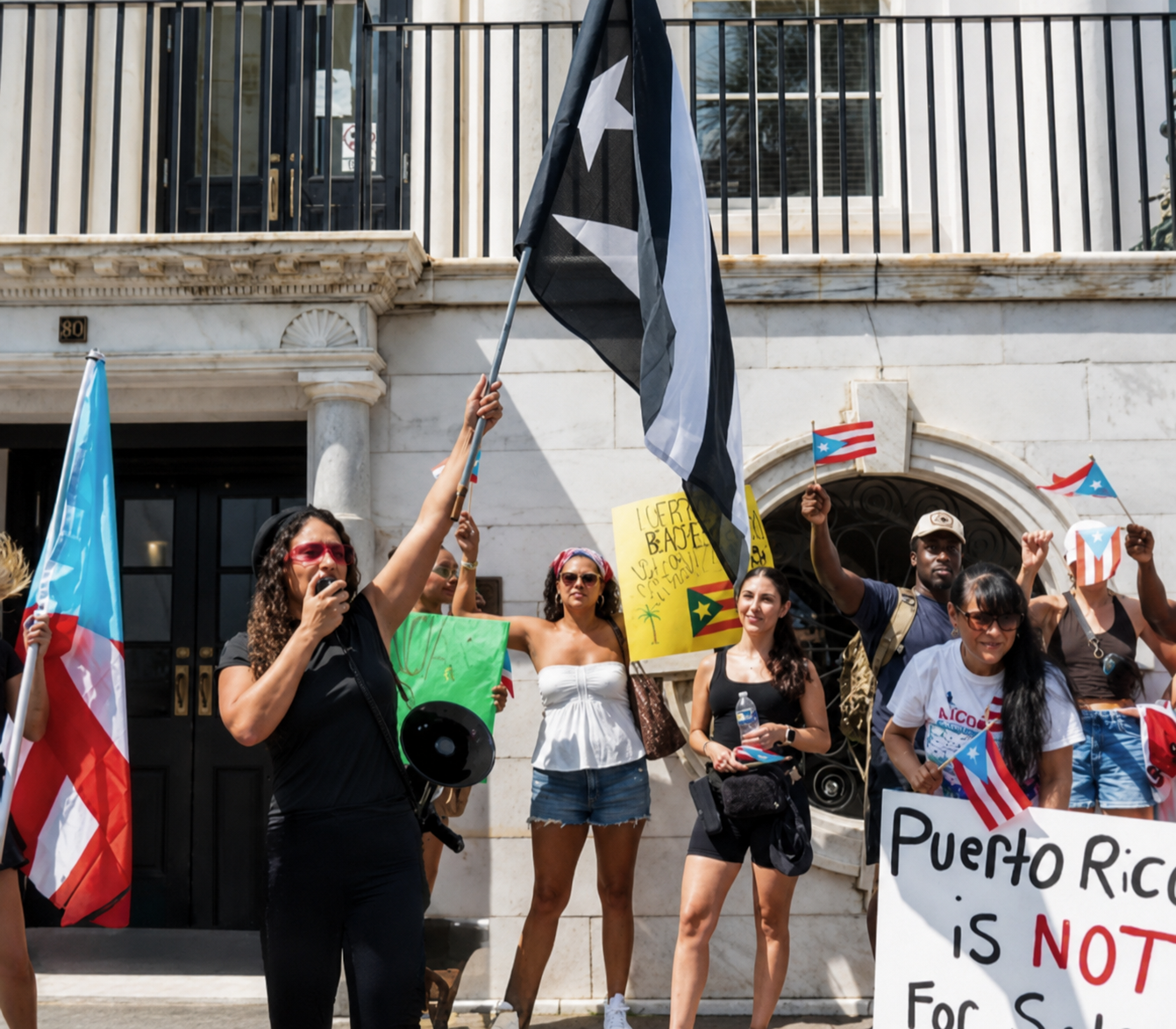 Rally speaker addressing a group holding Puerto Rican flags and signs.